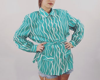 May include: A turquoise and white striped shirt with a long sleeve and a button-up front. The shirt has a belt and a pocket on the front.