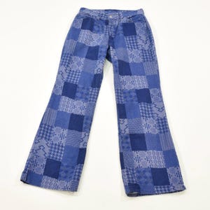 May include: Blue denim jeans featuring a patchwork design composed of various shades of blue and white geometric patterns. The pants have a standard waistband with a button closure, belt loops, and a straight-leg cut with a visible seam construction.