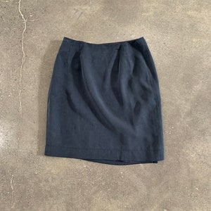 May include: A dark blue skirt with a straight, fitted silhouette. The skirt has a simple design with a smooth, even texture.
