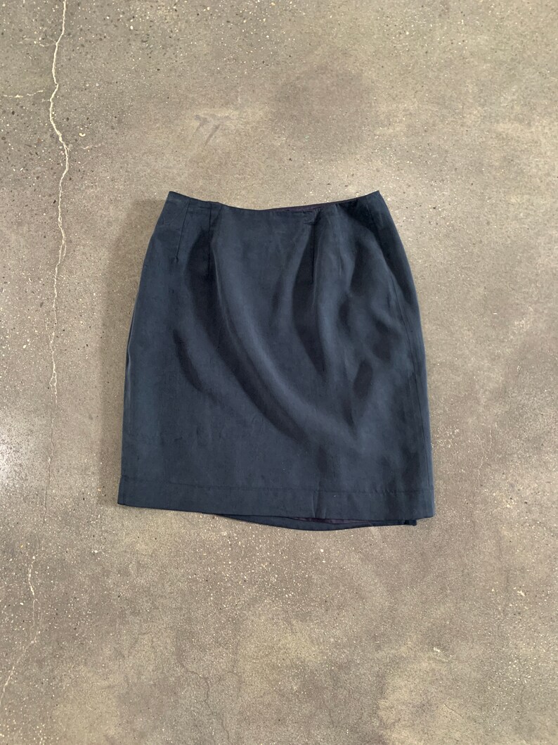 May include: A dark blue skirt with a straight, fitted silhouette. The skirt has a simple design with a smooth, even texture.