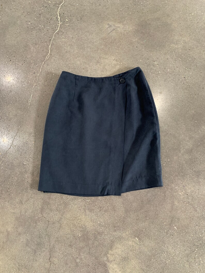 May include: A dark blue wrap skirt with a single button closure.