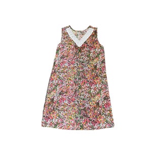 Könnte beinhalten: Ein ärmelloses Kleid mit Blumenmuster und einem weißen Spitzenkragen. Das Kleid hat ein pinkfarbenes, grünes und gelbes Blumenmuster.