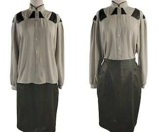 May include: A beige button-up blouse with black accents on the shoulders and a matching dark green skirt. The blouse has a high collar and long sleeves.