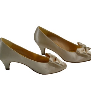 May include: A pair of ivory satin pumps with a small heel and a bow detail on the toe.