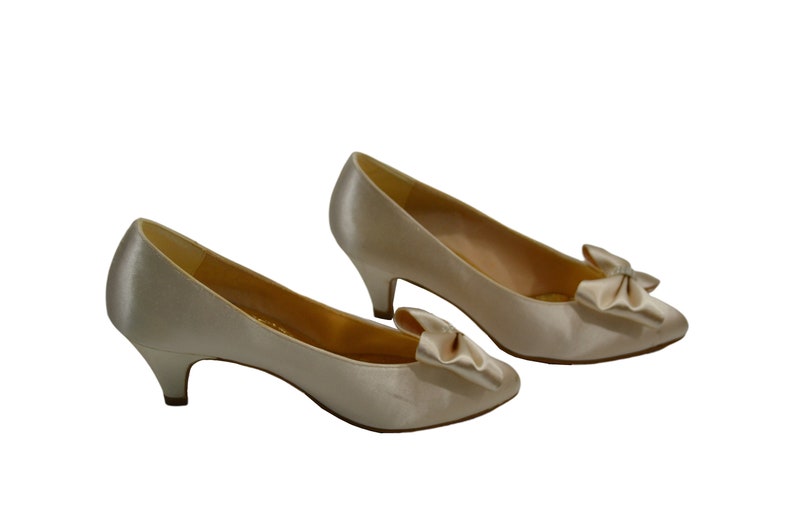 May include: A pair of ivory satin pumps with a small heel and a bow detail on the toe.