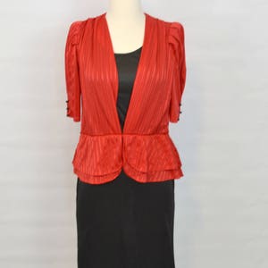 May include: A red and black dress with a ruffled top and a fitted skirt. The top has a V-neckline and short sleeves.