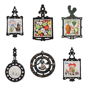 May include: Six vintage trivets with decorative ceramic tiles and ornate black metal frames. Designs include floral patterns, kitchen scenes, and a rooster. One trivet has the text "I'm not a slow cook, I'm a half-past cook."