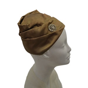 May include: A brown satin turban hat with a large rhinestone brooch.