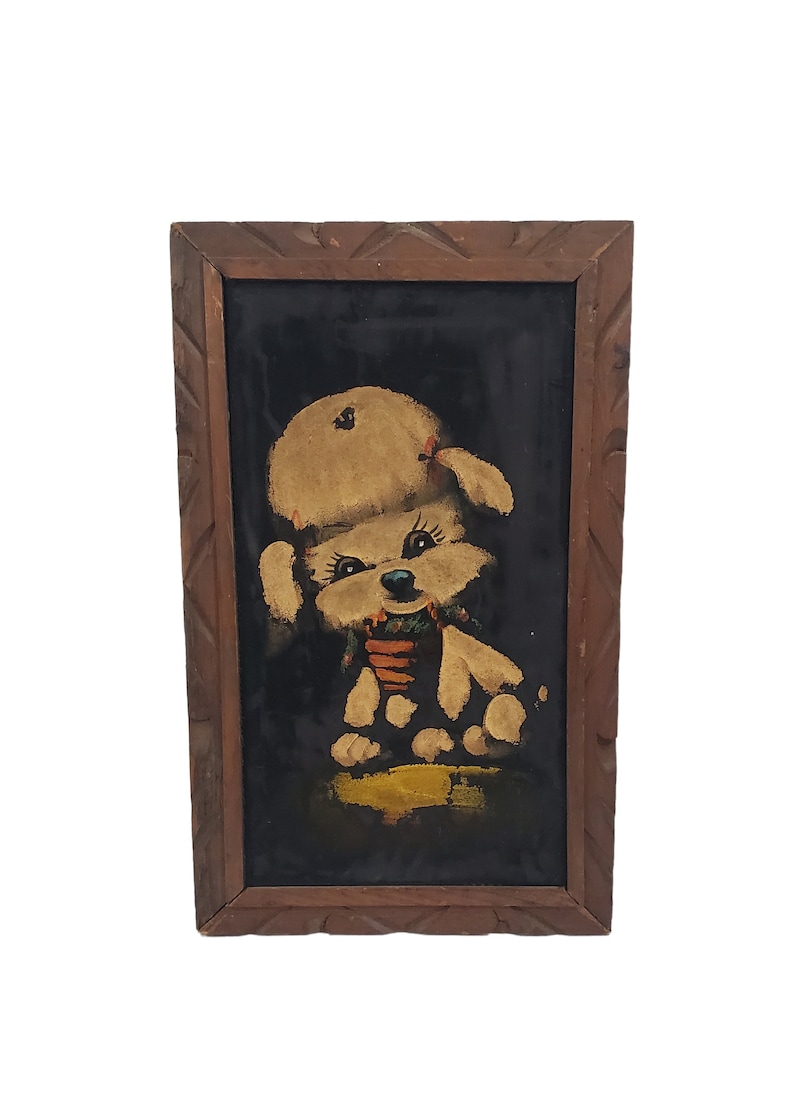 May include: A framed painting of a white poodle wearing a red bow and a hat, sitting on a yellow background. The painting is on a black velvet background.