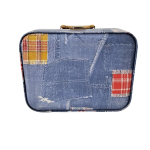 Pode incluir: Uma mala vintage com um design de patchwork de denim azul e xadrez. A mala tem uma alça marrom e uma forma retangular.