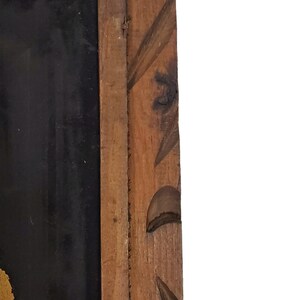 May include: A wooden frame with a carved design. The frame is dark brown and has a black background.