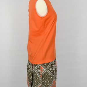 May include: A sleeveless orange top with a brown and white patterned skirt. The skirt has a geometric design with a paisley pattern.