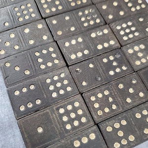 May include: A set of black dominoes with white dots. The dominoes are arranged in a grid pattern, with the dots on each domino facing up.
