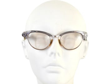 May include: Silver cat-eye glasses with clear lenses on a white mannequin head.