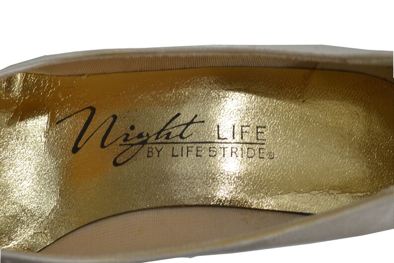 May include: Close-up of the inside of a shoe with a gold insole. The insole has the text "Night Life by Life Stride" printed on it.