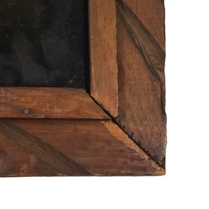 May include: Close-up of the corner of a wooden picture frame. The frame is made of dark brown wood with a diagonal pattern.