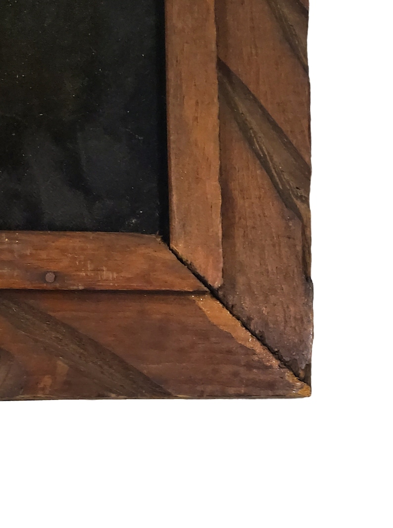 May include: Close-up of the corner of a wooden picture frame. The frame is made of dark brown wood with a diagonal pattern.