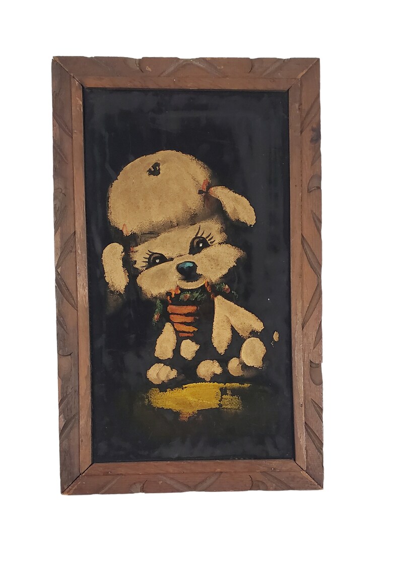 May include: A framed black velvet painting of a white poodle wearing a red bow and a green and orange scarf. The poodle is sitting on a yellow background.