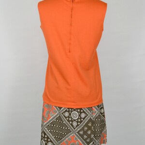 May include: A sleeveless orange top with a zip at the back, paired with a brown and white patterned skirt.