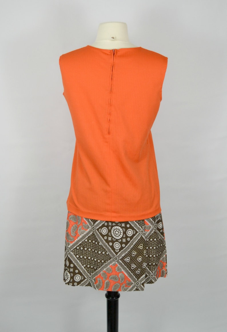 May include: A sleeveless orange top with a zip at the back, paired with a brown and white patterned skirt.