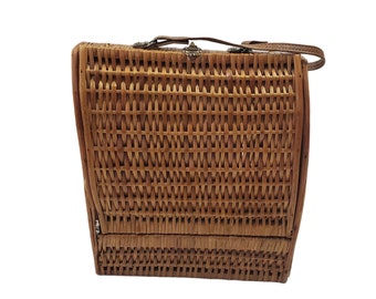 May include: A brown wicker picnic basket with a leather handle and a metal clasp.
