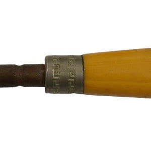 May include: A close-up of a yellow handled tool with a metal tip and a decorative band around the handle. The band has a repeating geometric pattern.