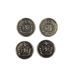 May include: Four silver-toned metal buttons with a raised heraldic crest design. Each button features a shield with a lion and scrollwork, and a decorative border. The buttons are round and have a slightly aged appearance.