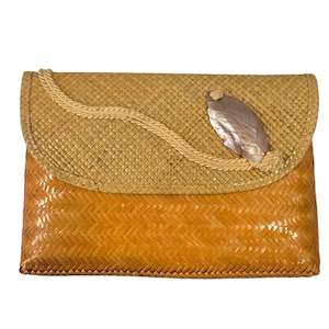 Puede incluir: Bolso de mano tejido con cierre de solapa. La parte superior es de color beige claro, con un ribete en forma de cuerda y un adorno nacarado en forma de hoja. La parte inferior es de color marrón dorado más oscuro, con un patrón tejido.