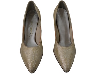 May include: A pair of gold glitter pumps with a pointed toe. The shoes have a label that reads "QualiCraft".