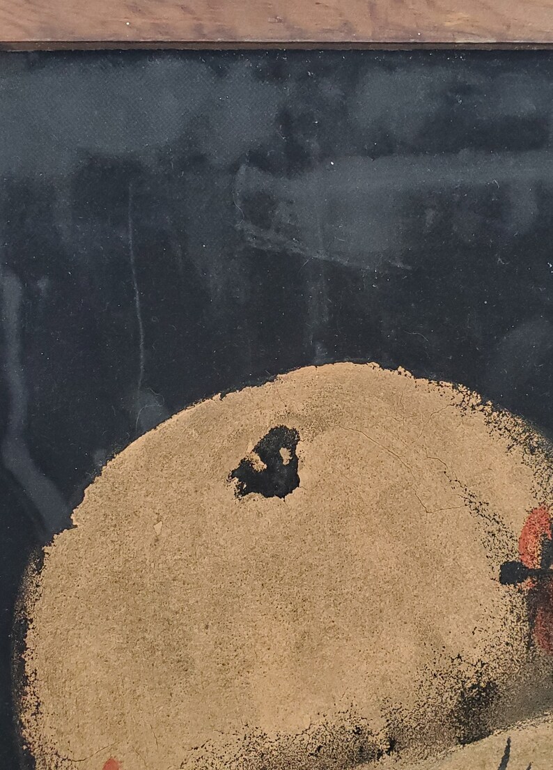 May include: A close-up of a black and gold abstract painting. The painting features a large, round, gold shape with a black centre. The background is black.