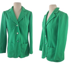 Könnte beinhalten: Ein grüner Blazer mit einem Reverskragen, zwei Pattentaschen und drei Knöpfen. Der Blazer befindet sich auf einem weißen Hintergrund.