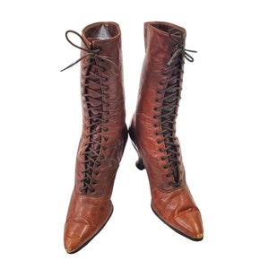 May include: A pair of brown leather lace-up boots with a pointed toe and a small heel.