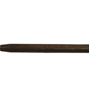 May include: A close-up of a brown wooden dowel rod with a pointed tip.