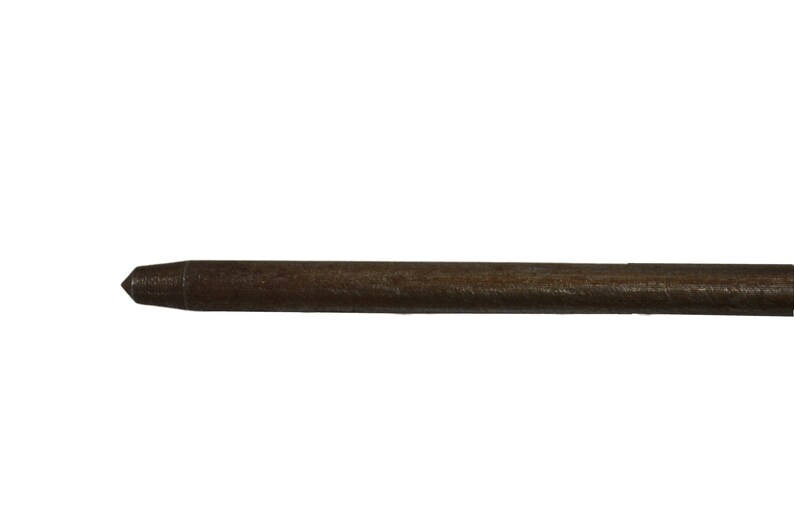 May include: A close-up of a brown wooden dowel rod with a pointed tip.