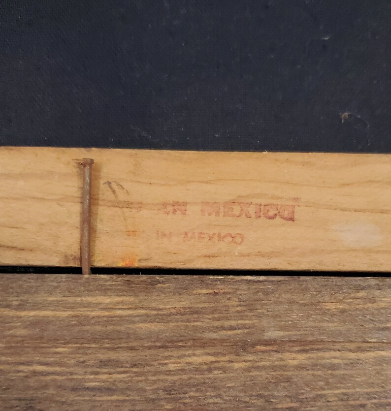 May include: Close-up of a wooden frame with a red stamp that reads "En Mexico" and "In Mexico".