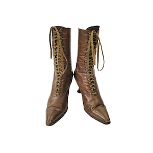 May include: A pair of brown leather lace-up boots with a pointed toe and a small heel.