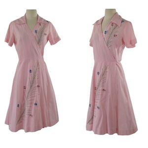May include: A pink and white striped wrap dress with short sleeves and a floral embroidery design.