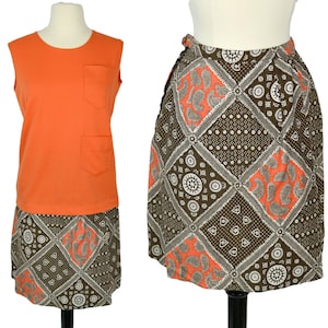 May include: A two-piece outfit featuring a sleeveless orange top and a brown and orange patterned skirt. The skirt has a geometric design with paisley accents.