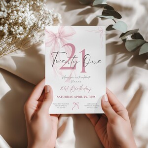 May include: A white invitation card with a pink bow and the text "Twenty One". The card also includes the text "Please join us to celebrate Emma's 21st Birthday" and event details.
