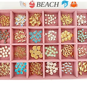 May include: A pink velvet jewelry organizer tray containing twenty-four compartments filled with various gold-tone metal charms. The charms feature beach-themed shapes including seashells, starfish, seahorses, palm trees, butterflies, and hearts.