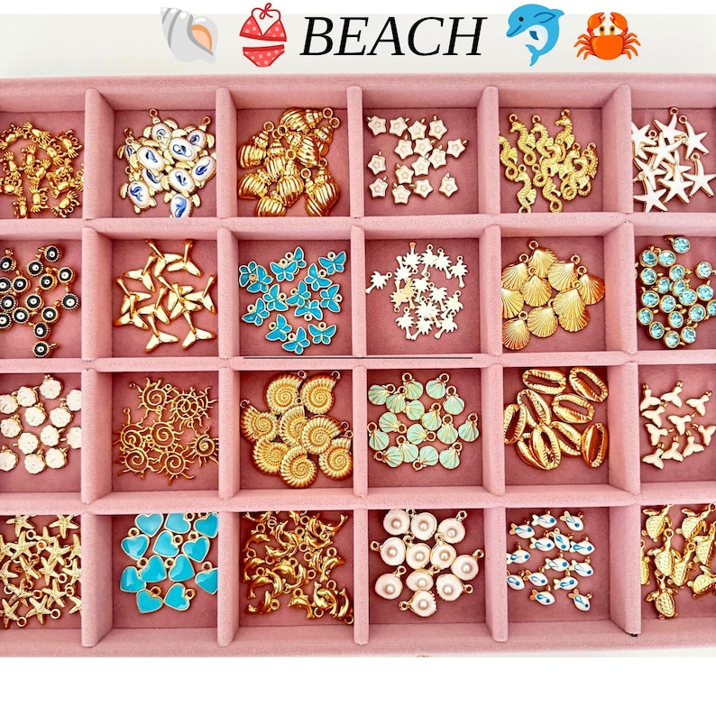 May include: A pink velvet jewelry organizer tray containing twenty-four compartments filled with various gold-tone metal charms. The charms feature beach-themed shapes including seashells, starfish, seahorses, palm trees, butterflies, and hearts.