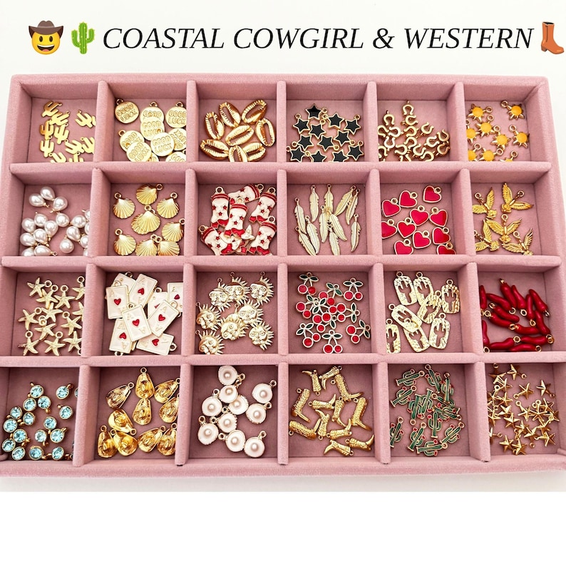 May include: A pink velvet jewelry tray with twenty compartments filled with assorted metal charms including gold cacti, cowgirl boots, seashells, stars, hearts, cherries, playing cards, and pearls. The text COASTAL COWGIRL & WESTERN is at the top.