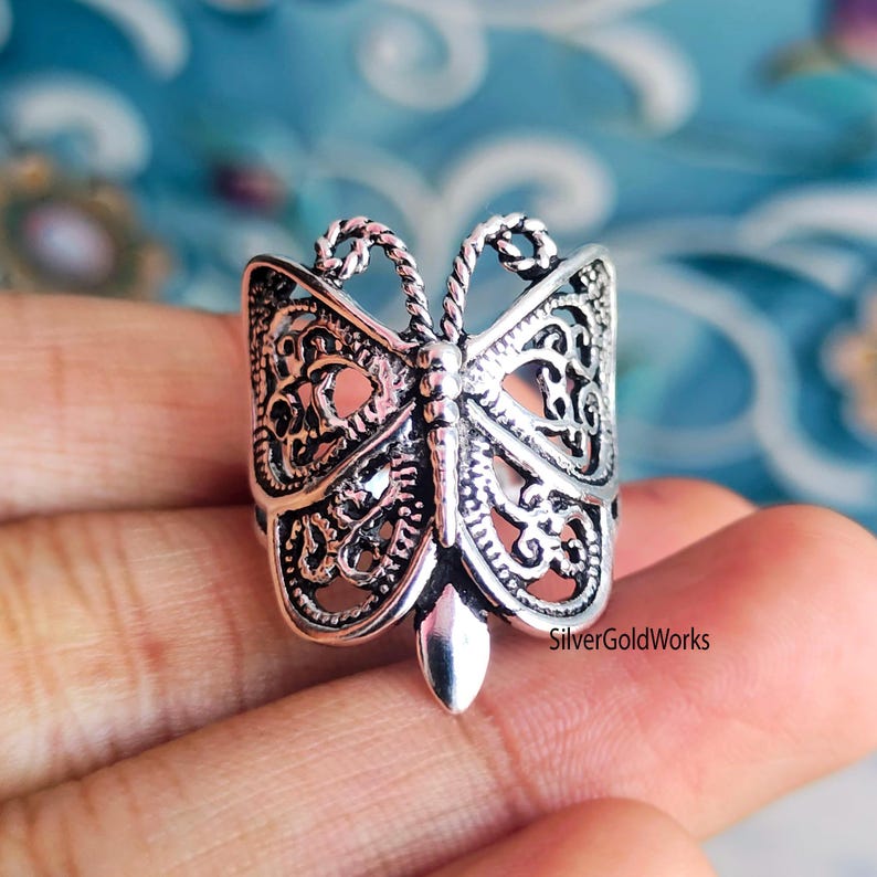 Puede incluir: Anillo de mariposa plateado con intrincados detalles de filigrana. El anillo presenta un dise&ntilde;o de mariposa detallado con alas caladas y un cuerpo central. El anillo es una pieza llamativa, perfecta para a&ntilde;adir un toque de elegancia inspirada en la naturaleza a cualquier atuendo.