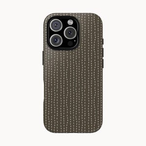 Op de afbeelding: Een donkerbruine telefoonhoes met een patroon van verticale witte stippellijnen. De hoes heeft een cameramodule met vier lenzen en een flitser. De hoes is ontworpen voor een smartphone.