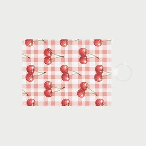 Op de afbeelding: Een rechthoekige kaarthouder met een herhalend patroon van rode kersen op een roze en witte ruitjesachtergrond. De kersen zijn afgebeeld in een aquarel-stijl, met groene steeltjes. Aan de rechterkant is een witte lus bevestigd.