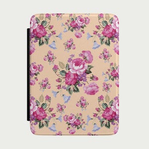 Op de afbeelding: Een rechthoekige hoes met een bloemenpatroon. Het ontwerp toont roze rozen, paarse accenten en blauwe klokvormige bloemen op een beige achtergrond. Aan de linkerkant is een zwarte band zichtbaar. De hoes heeft een getextureerd uiterlijk.