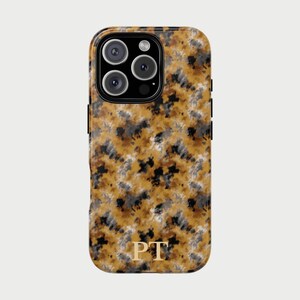 Op de afbeelding: Telefoonhoesje met een abstract patroon in goud, zwart en grijs. De hoes heeft een camera-uitsparing en de gouden initialen "PT" aan de onderkant. Ontworpen voor een smartphone.