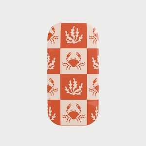 Op de afbeelding: Een rechthoekig object met een herhaald patroon van krabben en zeewier op een oranje en crème dambordachtergrond. Het object heeft afgeronde randen en een glanzende afwerking. Het ontwerp doet denken aan een maritiem thema.