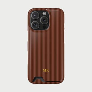 Op de afbeelding: Een bruine telefoonhoes met een verticaal gestreept patroon. De hoes heeft een uitsparing voor de camera en een kleine opening aan de onderkant. De initialen "MR" staan in gouden letters onderaan de hoes.