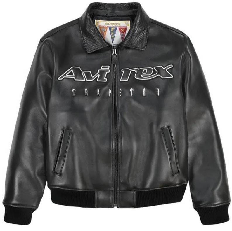 May include: Black leather jacket with a zip-up front, two front pockets, and a ribbed hem and cuffs. The jacket features the white text "Avi Rex TRAPSTAR" across the chest and a collar with a textured design.